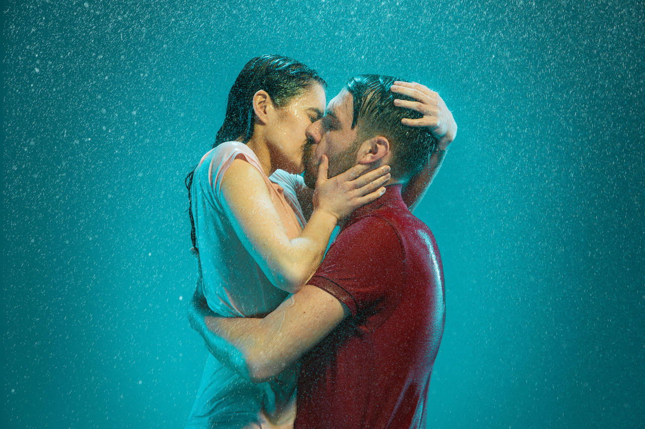 loving-couple-kissing-rain-turquoise-background_Easy-Resize.com